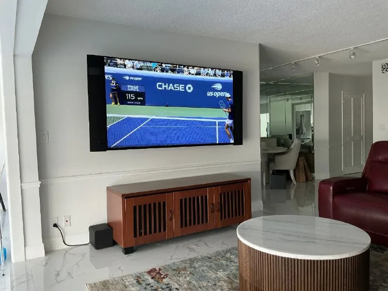 Wall-mounted television with vertical speakers on both sides above a media cabinet